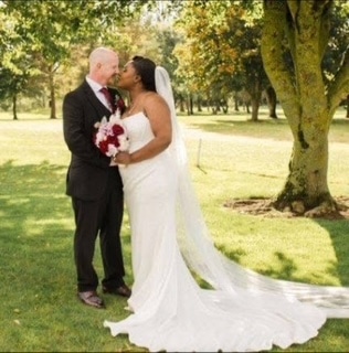Bride and groom kissing outdoors in a sunlit park.