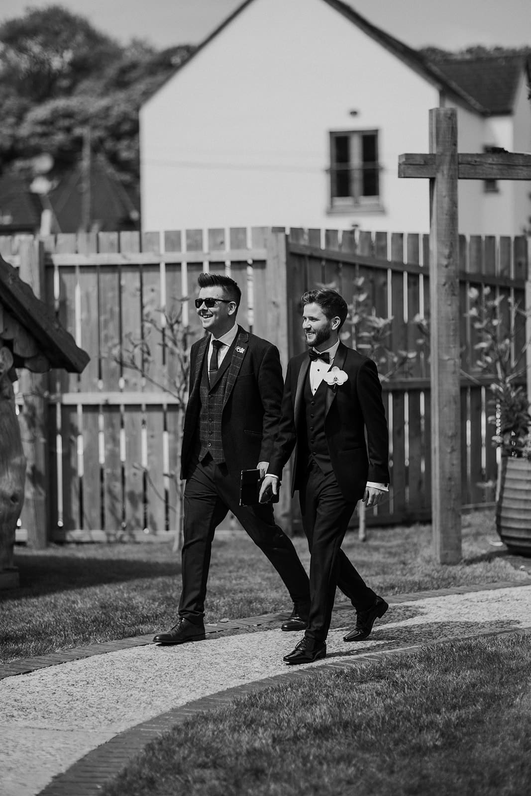 Two men in formal suits walking outdoors on a sunny day at The Rabbit Hotel.